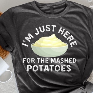 Puede incluir: Camiseta de color gris oscuro jaspeado con texto blanco que dice "Solo estoy aquí por el puré de patatas" y un gráfico de un tazón de puré de patatas.