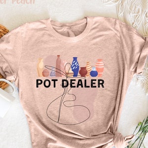 Puede incluir: Una camiseta marrón claro con un gráfico de varias macetas de colores y el texto "POT DEALER".