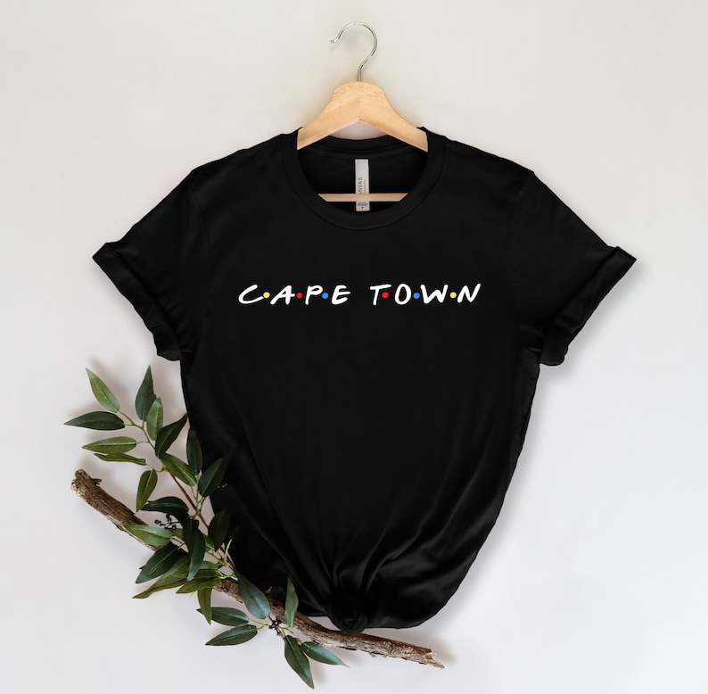 May include: Black t-shirt with a white graphic that says "C.A.P.E T.O.W.N" in the style of the "Friends" logo.