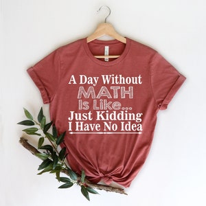 May include: A maroon t-shirt with white text that reads "A Day Without Math Is Like... Just Kidding I Have No Idea".