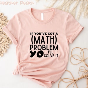 May include: A pink t-shirt with the text "If you've got a (MATH) problem yo I'll solve it" printed in black.