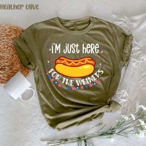 May include: A green t-shirt with the text "I'm just here for the weiners" and a cartoon hot dog with mustard and ketchup. The text is surrounded by red, white, and blue stars.