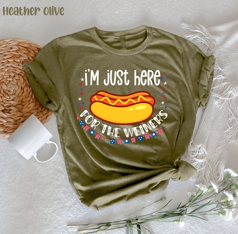 May include: A green t-shirt with the text "I'm just here for the weiners" and a cartoon hot dog with mustard and ketchup. The text is surrounded by red, white, and blue stars.