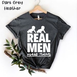 May include: Dark grey heather t-shirt with a white graphic of two babies crawling and the text "REAL MEN MAKE TWINS".
