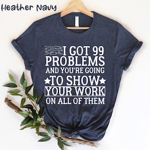 Puede incluir: Una camiseta azul marino jaspeada con texto blanco que dice "Tengo 99 problemas y vas a mostrar tu trabajo en todos".