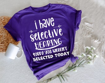 May include: Purple t-shirt with white text that reads "I have selective hearing. Sorry you weren't selected today."