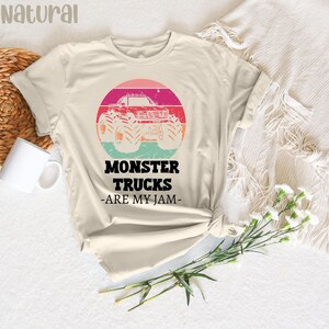 May include: A beige t-shirt featuring a vintage-style graphic of a monster truck with the text "Monster Trucks -Are My Jam- ".