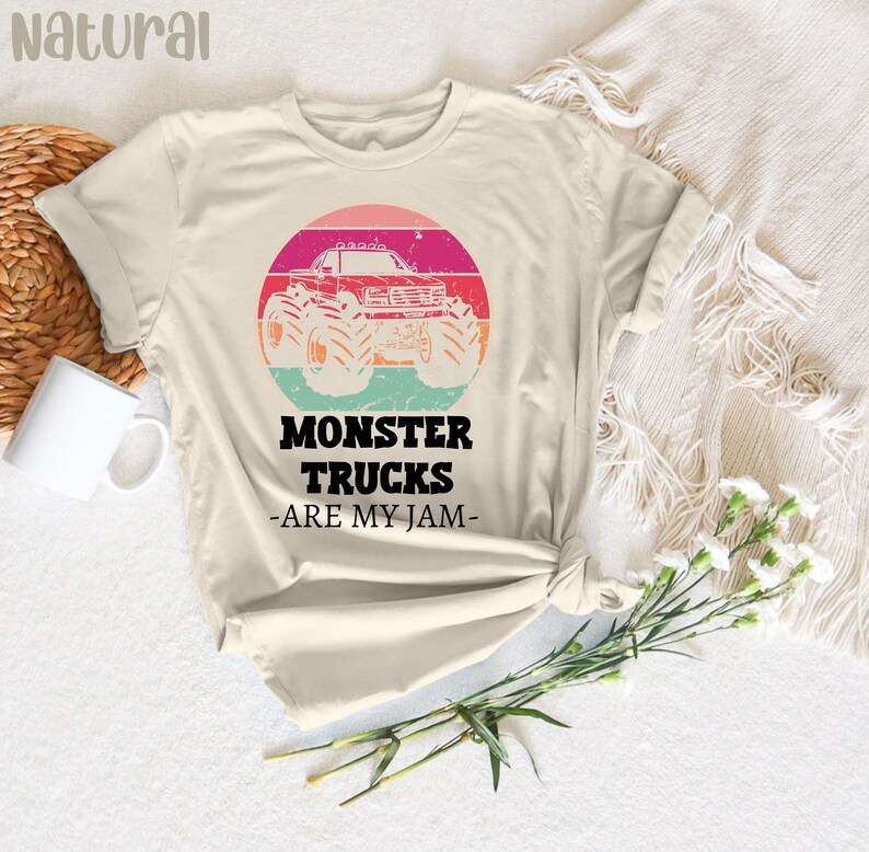 May include: A beige t-shirt featuring a vintage-style graphic of a monster truck with the text "Monster Trucks -Are My Jam- ".