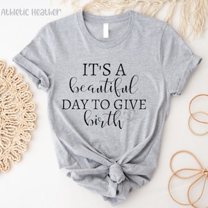 May include: Gray t-shirt with the text "It's a beautiful day to give birth" and a small footprint design.