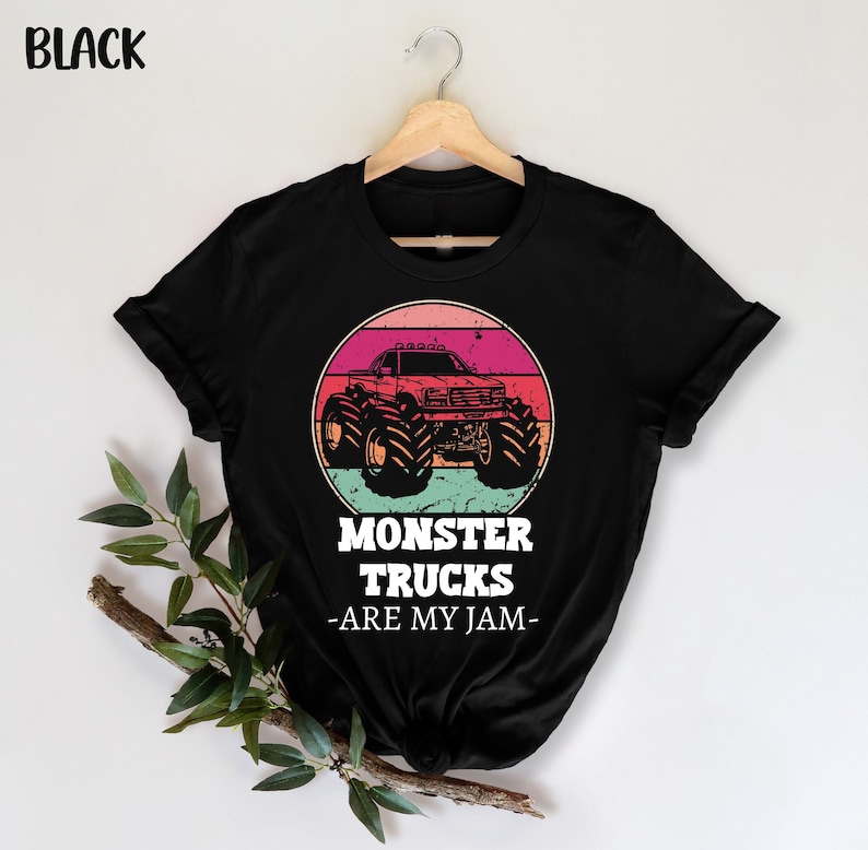 May include: Black t-shirt featuring a vintage-style graphic of a monster truck against a sunset backdrop. The text "Monster Trucks -Are My Jam- " is printed beneath the graphic.