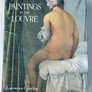 May include: A book titled "Paintings in the Louvre" by Lawrence Gowing. The cover features a classical painting of a nude figure seated on a bed. The figure has a head covering and is holding a cloth.