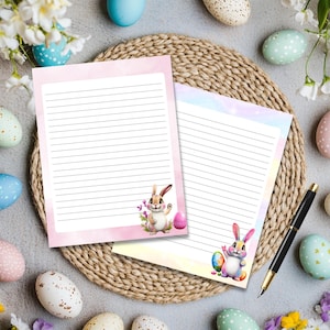 May include: Two printable stationery sheets with lined paper and a pastel background. Each sheet features a cartoon bunny holding an Easter egg. One sheet is pink and the other is blue.