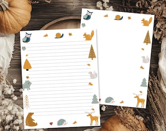May include: Two sheets of white stationery paper featuring a woodland theme. One sheet has horizontal lines, while the other is blank. Both are decorated with small illustrations of owls, squirrels, snails, hedgehogs, deer, and trees in autumn colors.