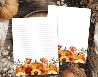 May include: Two sheets of white stationery paper featuring a horizontal arrangement of watercolor pumpkins, sunflowers, and autumn foliage at the bottom. One sheet contains thin horizontal lines for writing, while the other is blank.
