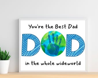 May include: Framed art print with the text "You're the Best Dad" above the word "DAD" in blue, with a handprint in the center. The phrase "in the whole world" is below. The print is in a white frame.