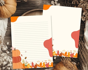 May include: Two sheets of stationery paper featuring autumn-themed designs. One sheet has horizontal lines and a stack of three pumpkins at the bottom left. Both sheets include orange and red abstract shapes and colorful fall leaves at the base.
