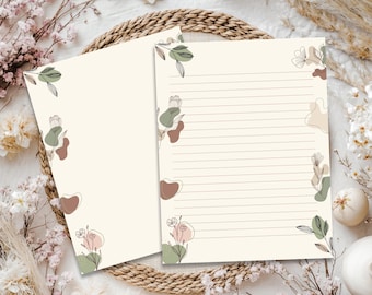 May include: Two sheets of cream-colored stationery paper featuring delicate black line art of flowers and leaves. The designs are accented with soft, abstract shapes in muted shades of sage green, dusty rose, and beige. One sheet is lined.