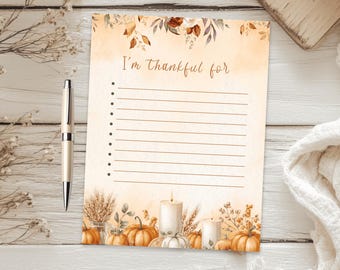 May include: A rectangular paper sheet with the text I'm thankful for at the top, featuring a list of ten blank lines with bullet points. The design includes watercolor illustrations of orange pumpkins, white candles, and dried foliage.