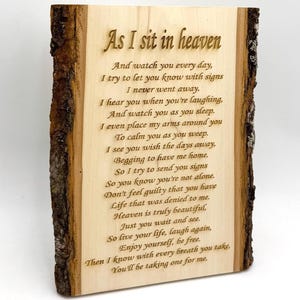 May include: A wooden plaque with a natural bark edge, featuring the engraved poem "As I sit in heaven." The text is in a serif font and is centered on the light-colored wood. The plaque is a memorial or decorative item.