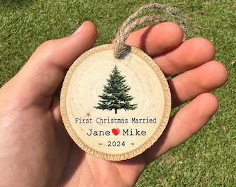 May include: A round wooden ornament with a small Christmas tree image and the text "First Christmas Married Jane ♥ Mike - 2024 - "