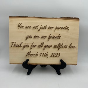 Puede incluir: Un letrero de madera con el texto "You are not just our parents, you are our friends. Thank you for all your selfless love. March 11th, 2023."