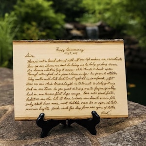 May include: A rectangular light-colored wooden plaque with natural bark edges, featuring dark brown laser-engraved cursive handwriting. The text begins with Happy Anniversary, Sept, 2017, Sire, followed by several lines of handwritten script.