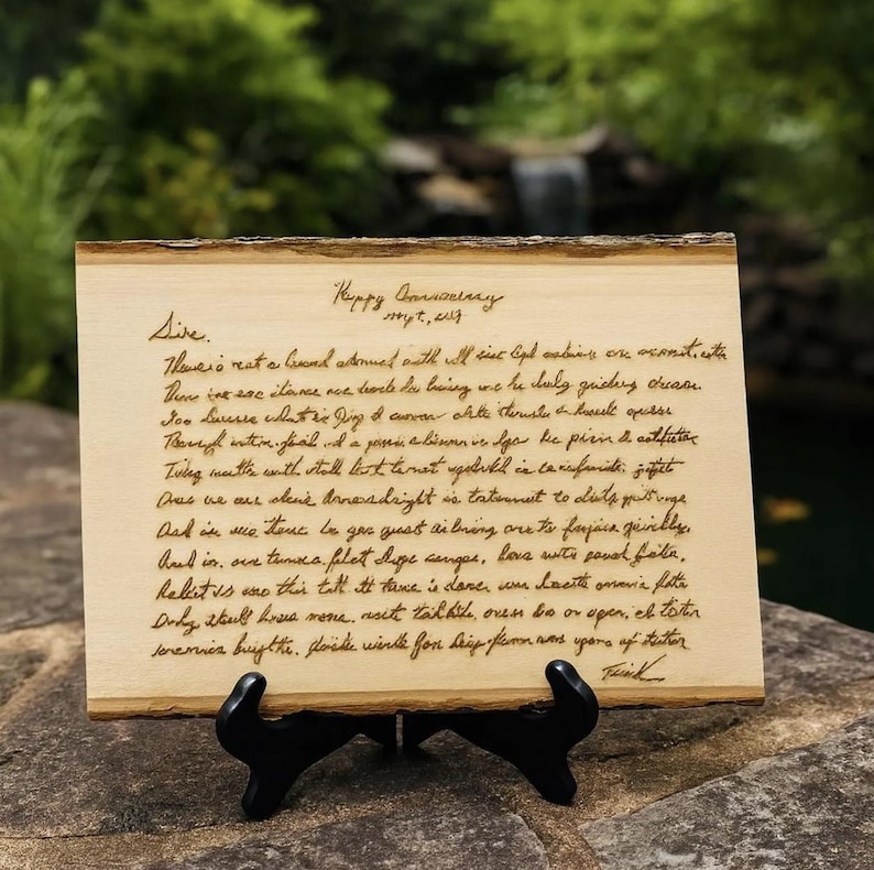 May include: A rectangular light-colored wooden plaque with natural bark edges, featuring dark brown laser-engraved cursive handwriting. The text begins with Happy Anniversary, Sept, 2017, Sire, followed by several lines of handwritten script.