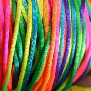 May include: A close-up of a bundle of colourful embroidery floss. The floss is arranged in a rainbow pattern, with each colour separated by a thin white line. The floss is soft and shiny, and it would be perfect for crafting projects.
