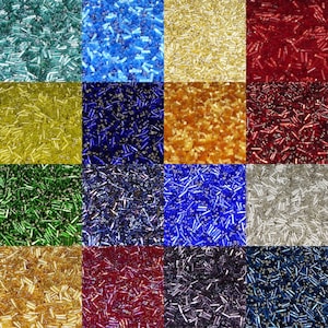 May include: A collection of 12 different colours of glass seed beads. The beads are arranged in a grid pattern. The colours are: teal, light blue, gold, red, yellow, dark blue, green, purple, blue, silver, burgundy, and navy.