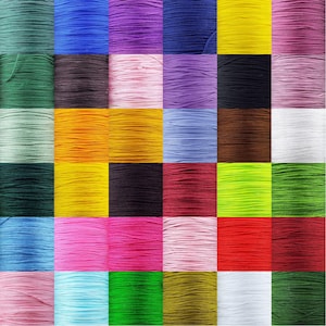 May include: A collection of 36 spools of colourful thread, each wound with a different colour of thread. The spools are arranged in a grid pattern, with each row and column containing a different colour.