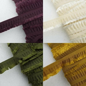 May include: Four spools of ruffled trim with frayed edges. The trim is shown in four colours: burgundy, cream, olive green, and mustard yellow.