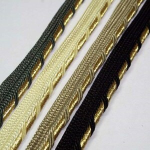May include: Four different colours of trim with a gold accent. The trim is made of a woven fabric and has a decorative edge.