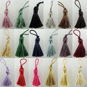 May include: Assortment of 20 small tassels in various colours, including pink, green, black, grey, brown, blue, purple, red, and gold. The tassels are approximately 2 inches long and are made of soft, silky yarn.