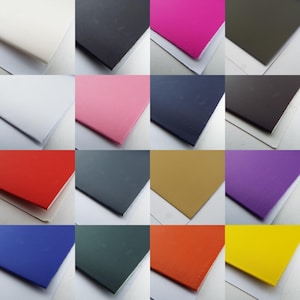 May include: A collection of 16 fabric swatches in various colours. The swatches are arranged in a grid pattern, with each swatch measuring approximately 25 cm by 25 cm. The colours include white, black, pink, navy blue, red, grey, brown, purple, blue, green, orange, and yellow.