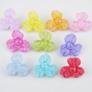May include: Assortment of ten colourful plastic flower-shaped buttons with a lace design. The buttons are in shades of pink, purple, blue, green, yellow, and orange.