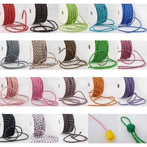 May include: Assortment of spools of colourful, patterned, and solid cord. The cords are wound around white spools and are displayed in rows.