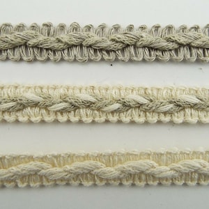 May include: Three samples of braided trim, one in natural white, one in a light beige, and one in a darker beige.