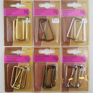May include: Six packs of metal buckles for adjusting straps. Each pack contains two buckles in gold, silver, or antique brass finishes. The packs are labelled with the brand name "MEDIAC" and the size "38 mm".
