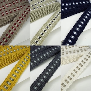 May include: Assortment of woven ribbon trim in various colours, including red, white, black, grey, beige, and yellow. The ribbon features a checkered pattern with white squares.
