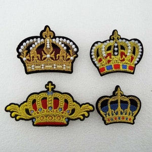 May include: Four embroidered iron-on patches featuring different styles of gold crowns with red, blue and white accents. The crowns are on a white background.