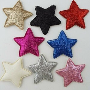 May include: Eight glitter star shapes in various colours, including gold, black, red, pink, white, silver, blue, and fuchsia. The stars are made of felt and have a 3D effect.