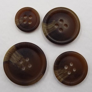 May include: Set of four brown and beige buttons with four holes each. The buttons have a mottled pattern.