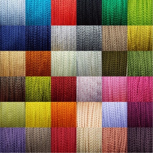 May include: A collection of 24 spools of colourful waxed cord. The cords are arranged in a grid pattern, with each spool showing a different colour. The colours include red, blue, green, yellow, orange, purple, pink, brown, white, black, and grey.