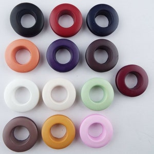May include: Assortment of 14 colourful plastic grommets in various colours, including black, red, purple, brown, white, green, orange, and pink.