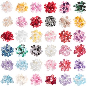 May include: Assortment of colourful plastic buttons in various shapes, including hearts, stars, flowers, and circles. The buttons are arranged in rows on a white background.