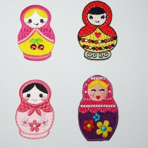 May include: Four embroidered iron-on patches featuring different designs of Russian nesting dolls. The dolls are all wearing traditional clothing and have smiling faces. The patches are perfect for adding a touch of whimsy to clothing, bags, or other fabric items.