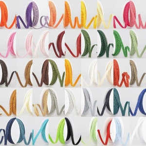 May include: Assortment of 25 spools of colourful, textured ribbon. Each spool is wound with a different colour of ribbon, including red, blue, green, yellow, orange, purple, brown, and white.