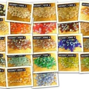 May include: Assortment of small, round, iridescent glass beads in various colours, including blue, green, red, orange, yellow, and white. The beads are arranged in rows on a wooden surface.