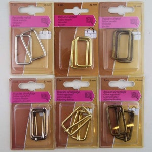 May include: Six packs of metal buckles in silver, gold, and bronze. Each pack contains two rectangular buckles, measuring 32 mm. The packaging is labelled with the text "Adjusting buckles" and "Buckles".