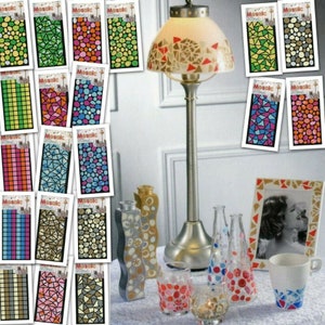 May include: A collection of mosaic sticker sheets with various designs, including geometric shapes, pebbles, and squares. The stickers are shown on a lampshade, vases, a picture frame, and a mug.